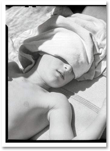 The alt text for the image is: "Black and white photo of a sleeping baby on a book."