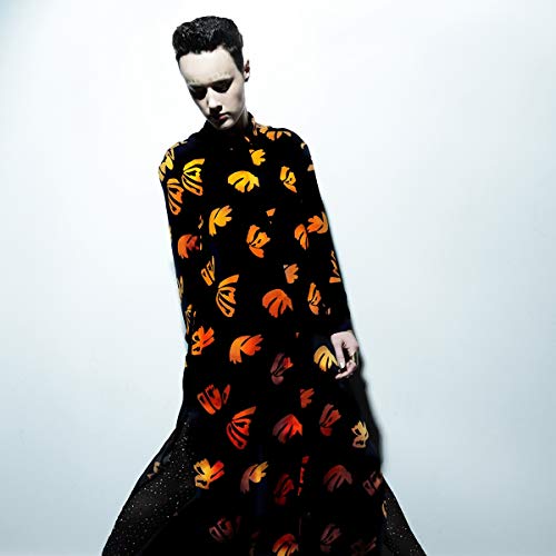 Man in a black shirt with orange and yellow floral pattern against a white background.