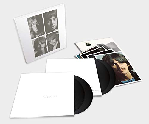 "White vinyl record album with sleeve and photos, partially open, showing black vinyl discs inside."