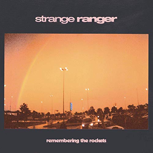 "CD cover with a rainbow over a parking lot at sunset, on dark grey background."