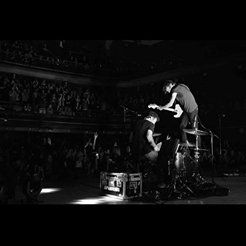 "Black and white photo of Japandroids performing on stage with a crowd in the background."