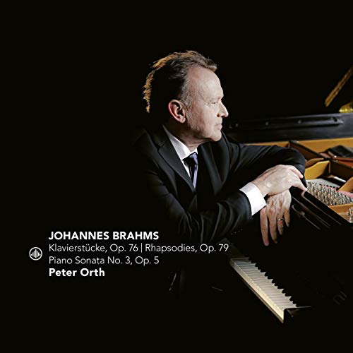 Man in a black suit sitting at a piano with text overlay on a black background.