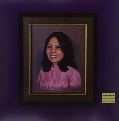 A framed portrait of a smiling woman with dark hair and pink shirt.