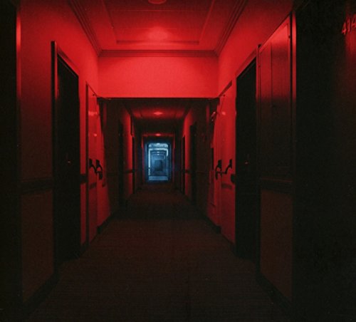 "Dimly lit hotel corridor with red lighting and numbered doors."