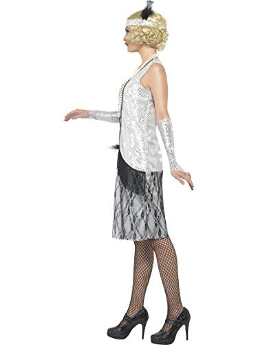 The image shows a woman wearing a 1920s flapper costume, including a silver sleeveless top, a black and silver skirt with fringe, fishnet stockings, and black heels. She has blonde hair and is accessorized with a headband, a long glove, and a beaded necklace. Alt text: Woman in 1920s flapper costume with silver top, fringe skirt, and fishnet stockings.