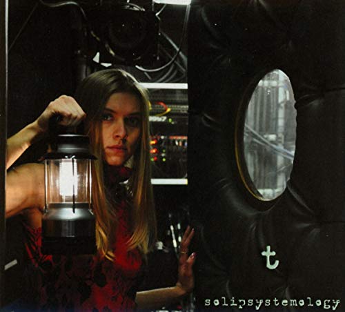 A woman holding a lantern, beside a large black tire, on a music CD cover.