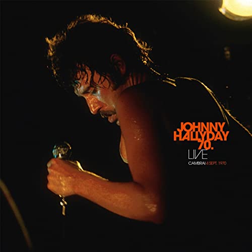 Johnny Hallyday singing into a microphone on a dark album cover.