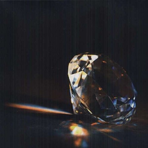 A large, faceted crystal on a dark surface, reflecting light.