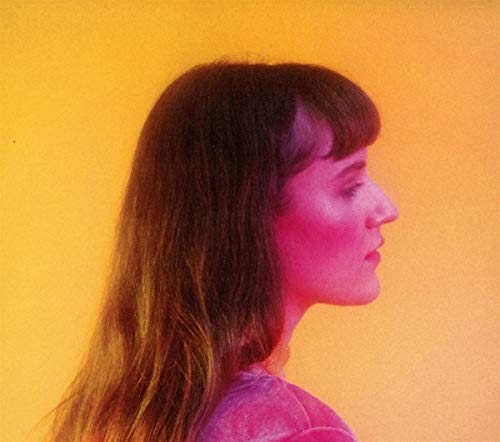 A woman with long brown hair and bangs against a bright yellow background.