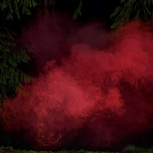 A red smoke cloud is surrounded by green trees in a dark setting.