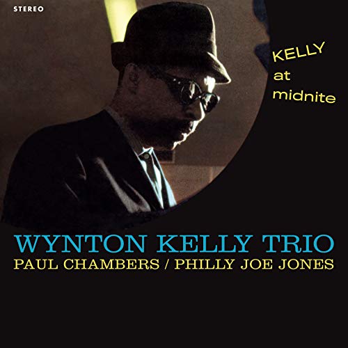 "Album cover with a man in a hat and sunglasses playing piano."