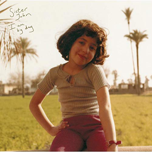 Album cover with a young girl sitting outdoors, smiling, with palm trees in the background.