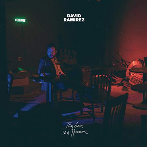 "Album cover with man sitting at a table in a dimly lit room."