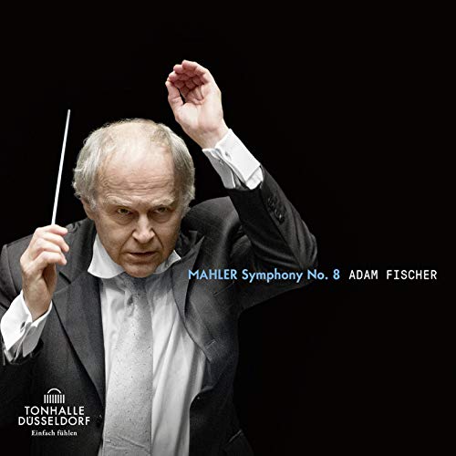 Conductor Adam Fischer in a black suit, holding a baton, against a black background.