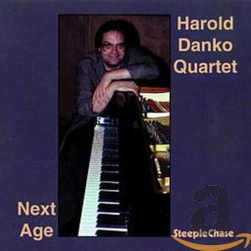 CD album cover with a man sitting at a piano, on a gray background.