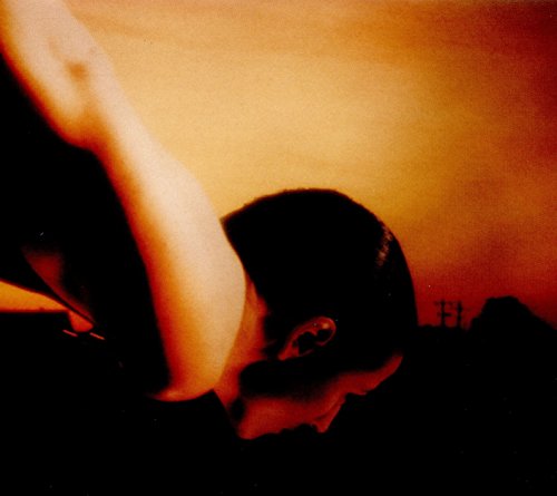 The alt text for this image is: "Album cover featuring a person with a raised arm against an orange background."