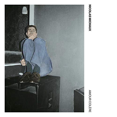 "CD cover with a man sitting on a box, covering his face."
