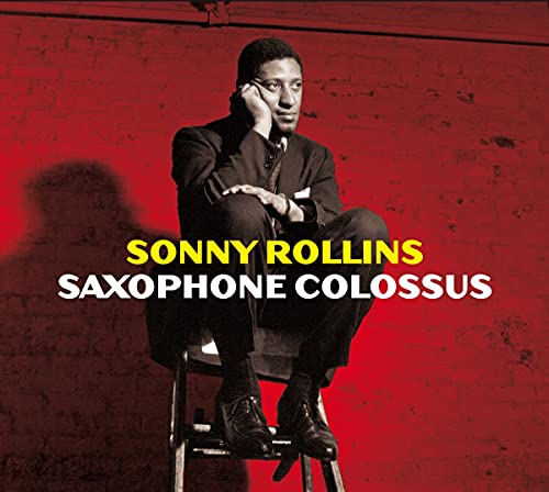 "Album cover with a man sitting on a stool against a red background."