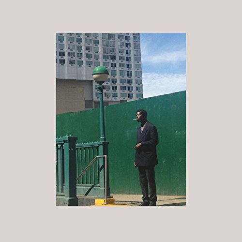 Album cover with a man standing by a green wall and lamp post.