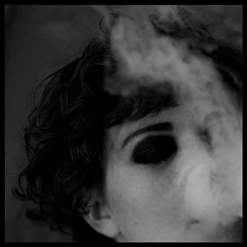 Black and white close-up portrait of a person with dark eye makeup and smoke.