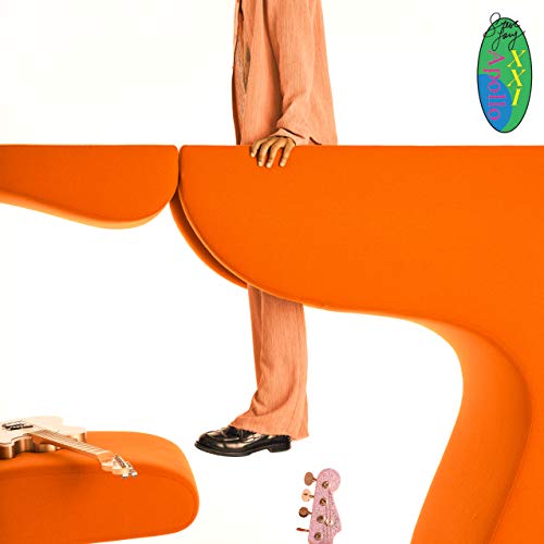 The alt text for the image is: "Person in orange outfit standing behind orange abstract shape with guitar."
