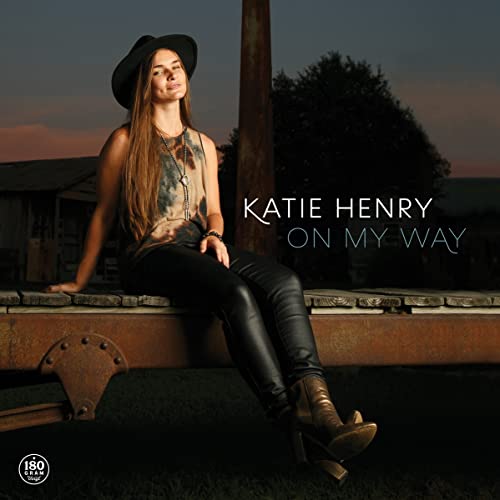 Katie Henry album cover: woman in hat leaning on weathered wood.
