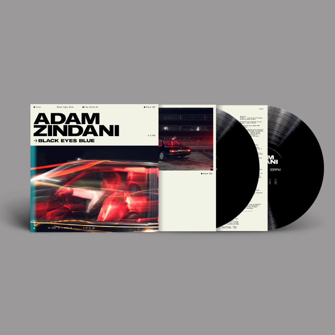"Vinyl record sleeve with black vinyl and white cover, featuring a red car image."
