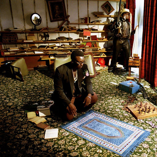Compact disc with a man sitting on the floor in a cluttered room.