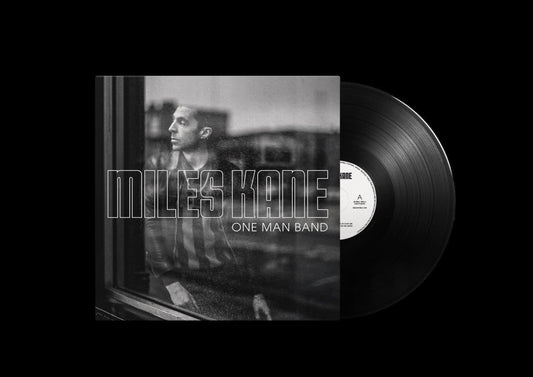 "Black vinyl record with white label and album cover featuring a man by a window."