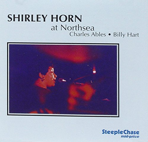 Jazz album cover with a musician playing piano on a dimly lit stage.