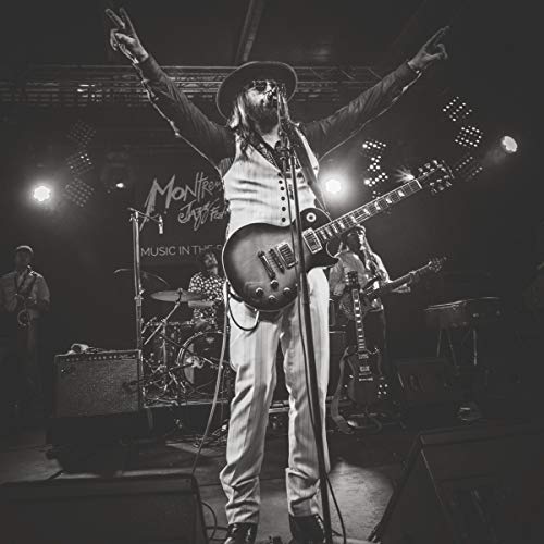 "Black and white image of a man performing on stage with a guitar."