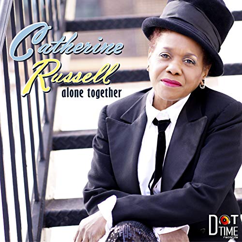 Catherine Russell album cover: woman in black suit and hat sitting on stairs.