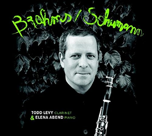 Black-and-white image of a man holding a clarinet, surrounded by dark leaves.