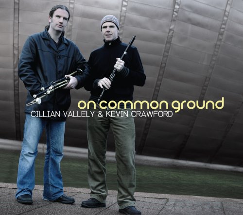 "CD cover featuring two men holding musical instruments, standing in front of a metal wall."