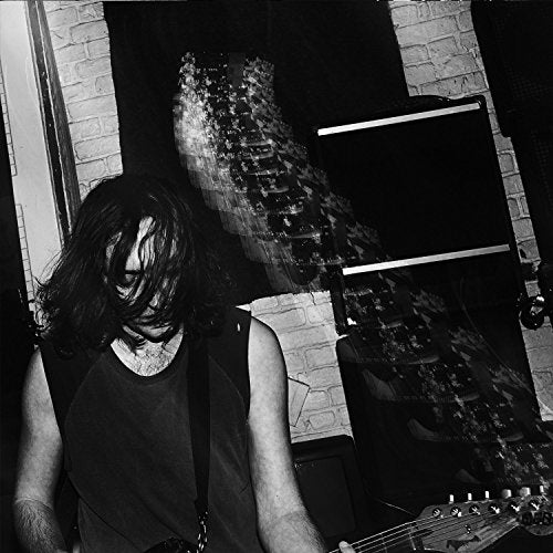 Black and white image of a man playing guitar in a recording studio.
