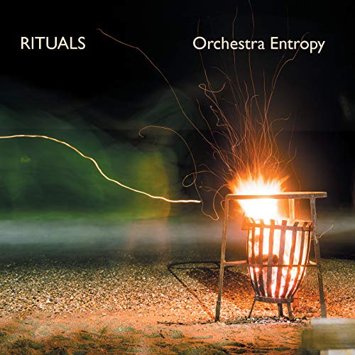"Album cover with a metal fire pit on gravel, surrounded by sparks at night."
