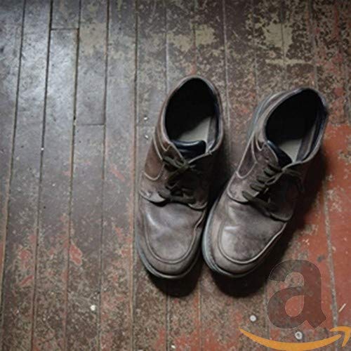 A pair of worn, dark brown leather shoes on a worn, wooden floor.