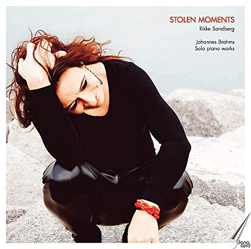 Woman crouching on rocky ground, wearing black, with red bracelets and title text above.