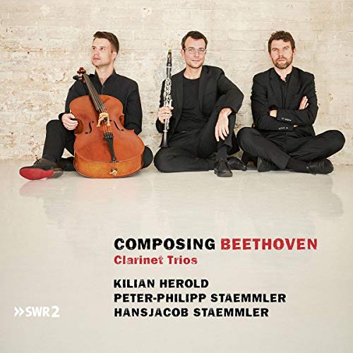 "CD cover with three men sitting on the floor holding musical instruments."