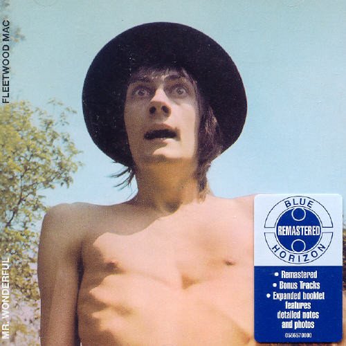 "Album cover: shirtless man in hat with doll, trees in background."