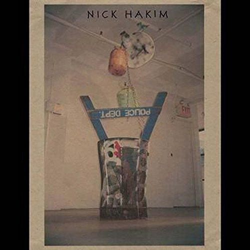 Vinyl record cover featuring a sculpture with hanging objects and a police sign.