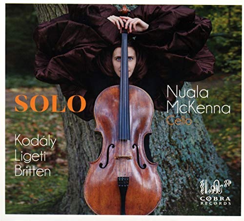 Woman in brown dress leaning on tree, holding a cello, on a CD cover.
