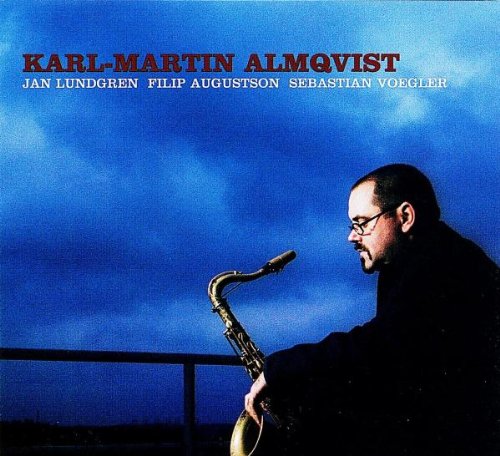 "Saxophonist in dark attire plays instrument against a blue sky with red and white text."