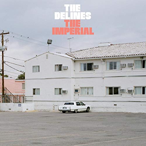 The image shows a white building with a white car, representing a music album cover.