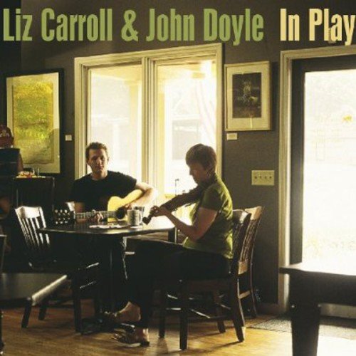 Album cover: two musicians playing guitars at a table, indoors, with text at the top.