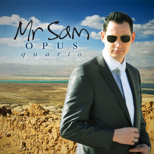 Man in a black suit and sunglasses stands in a desert landscape.