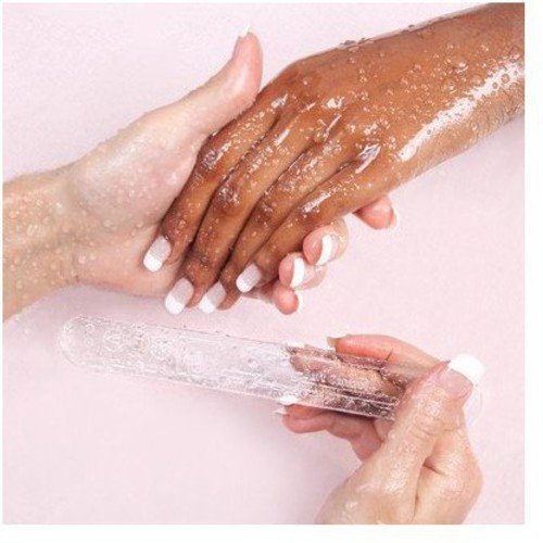 A hand holding a clear, cylindrical object, with soapy hands above, on a pink background.