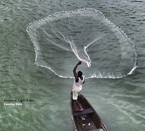 A man in a boat casts a large fishing net into the water.