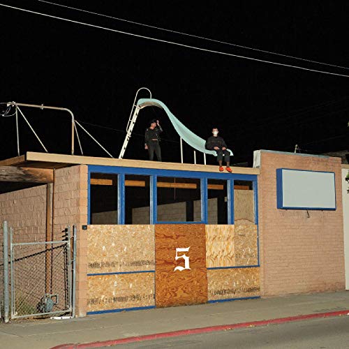 "Two men on a building rooftop at night, with a slide."
