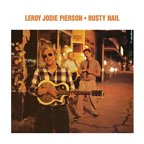 "Album cover with man holding guitar on a city street at night."